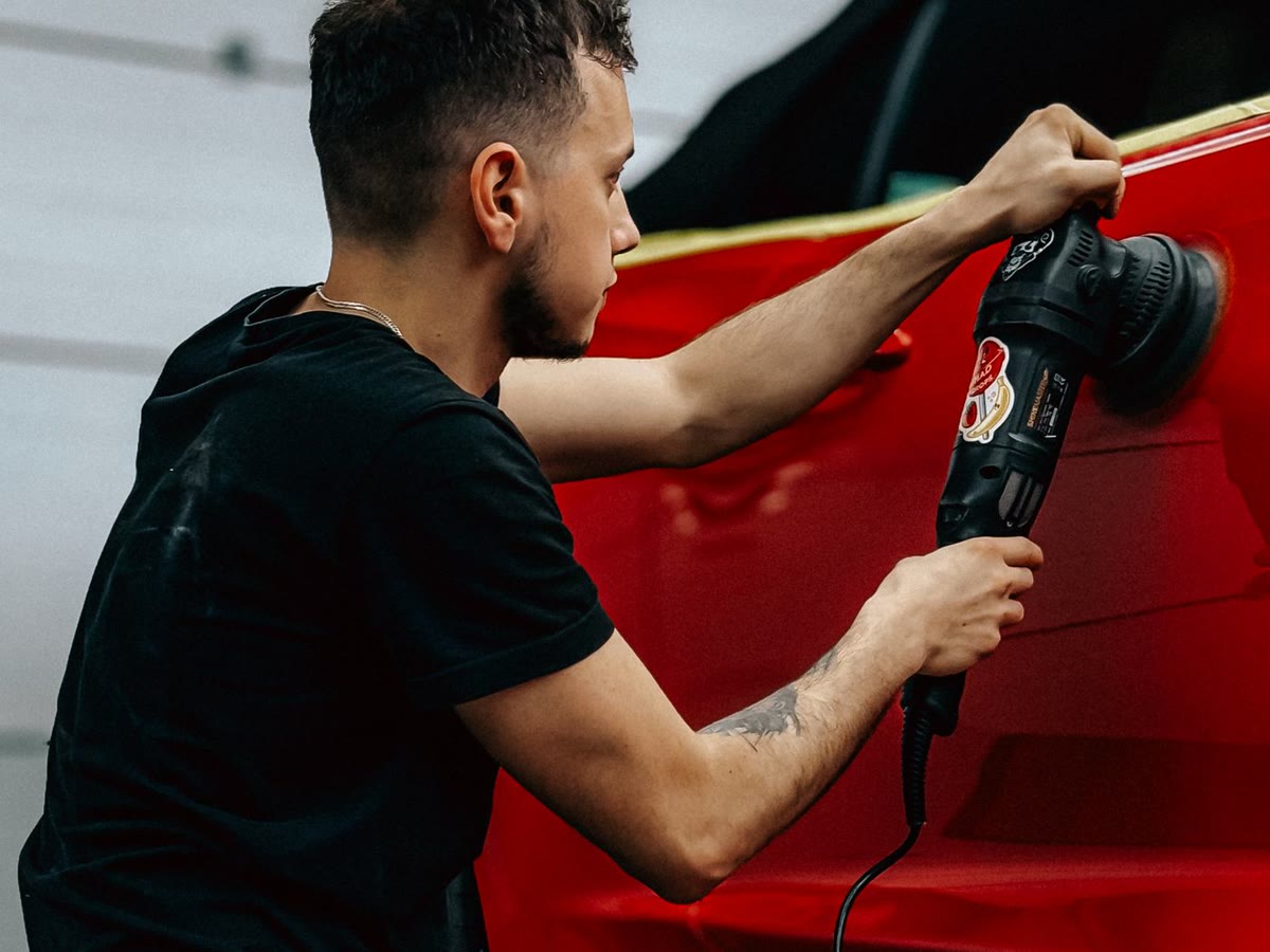 Specialist care finisează vopseaua unui automobil roșu